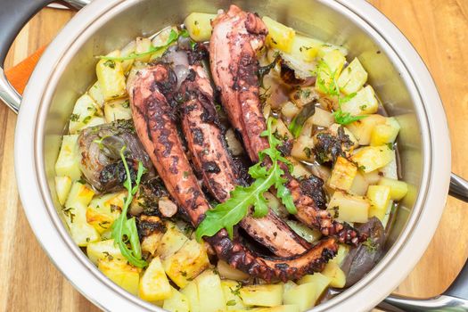 Grilled octopus. Grilled octopus on grill pan with potato - ready to eat. Sprinkle with chopped parsley and minced garlic.