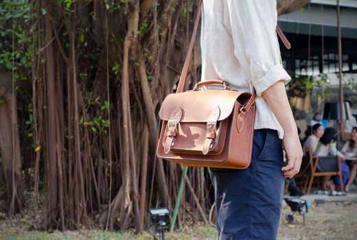 Fashion man holding a brown leather bag