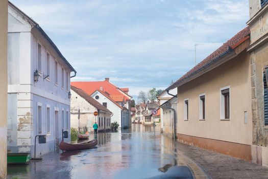 Rural village houses in floodwater. Road with the river overflown with the residents in their homes. Floods and flooding the streets. Natural disaster.  