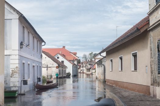Rural village houses in floodwater. Road with the river overflown with the residents in their homes. Floods and flooding the streets. Natural disaster.  