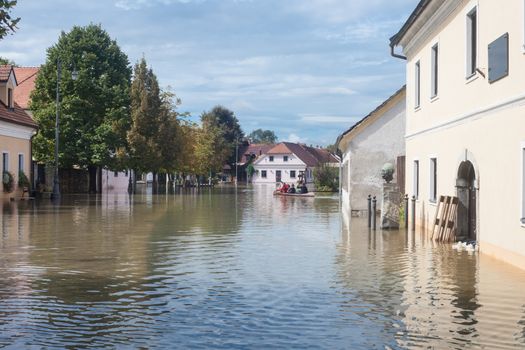 Rural village houses in floodwater. Road with the river overflown with the residents in their homes. Floods and flooding the streets. Natural disaster.  