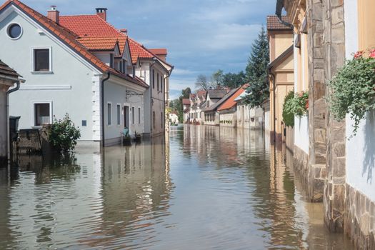 Rural village houses in floodwater. Road with the river overflown with the residents in their homes. Floods and flooding the streets. Natural disaster.  