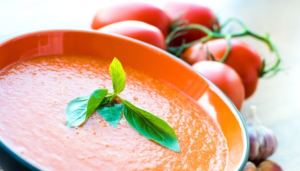 A bowl of tomato soup gaspacho with basil, tomatoes and garlic