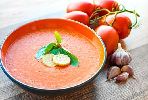 A bowl of tomato soup gaspacho with basil and crackers