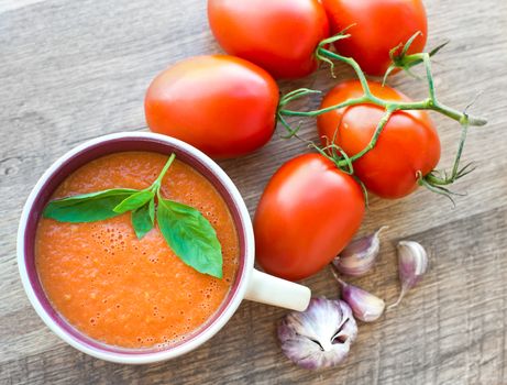 Bowl of tasty tomato soup gaspacho with basil, tomatoes and garlic