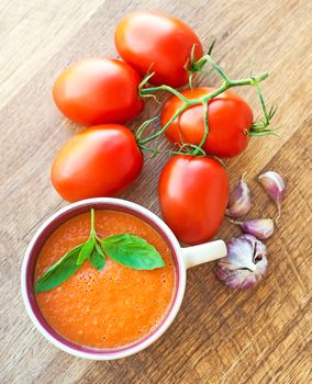 A bowl of tomato soup gaspacho with basil, tomatoes and garlic