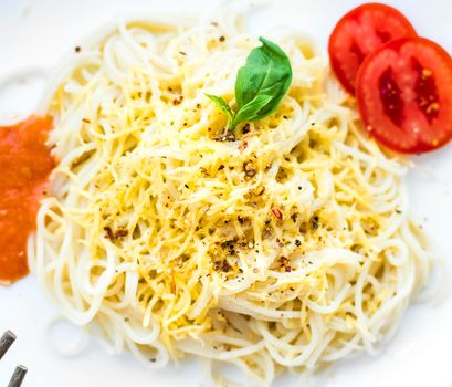 Tasty spaghetti dinner with sauce and basil close up