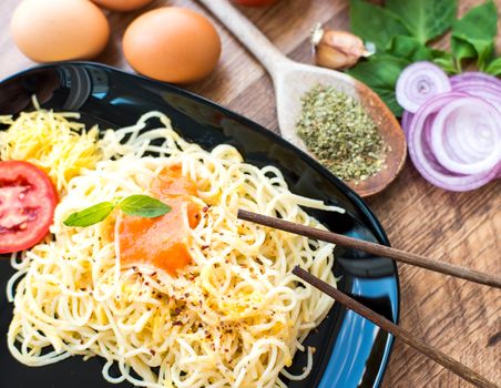Tasty spaghetti dinner with sauce, basil and chopsticks close up