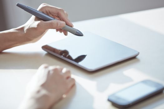Hands of designer working with tablet PC and stylus