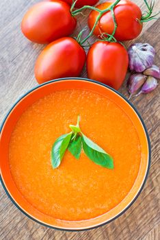 A bowl of tomato soup gaspacho with basil, tomatoes and garlic