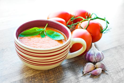 A bowl of tomato soup gaspacho with basil, tomatoes and garlic