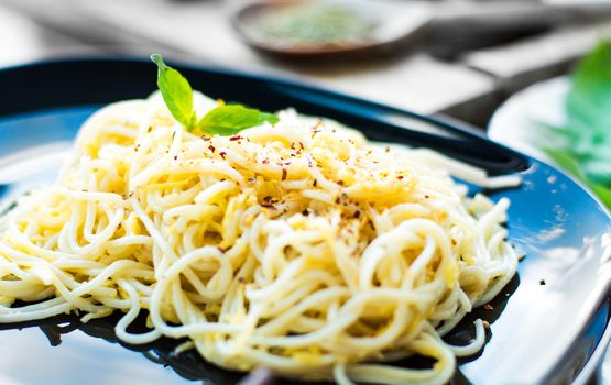Tasty spaghetti dinner with cheese and basil close up