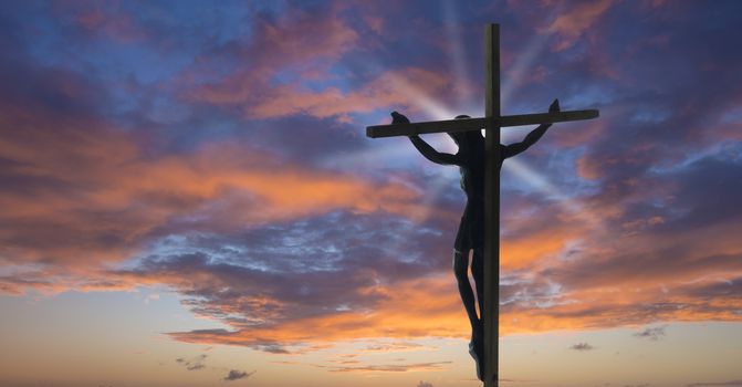 Jesus Christ on the Cross with sunset clouds as a background