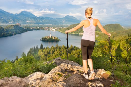 Young spoty active lady with hiking sticks admiring beautiful nature around Bled Lake in Julian Alps, Slovenia. 