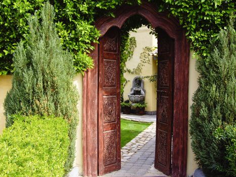 Carved wood doors lead to garden with fountain