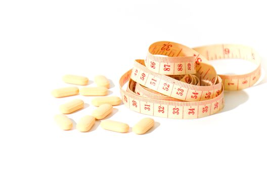 pills and measuring tape on a white background