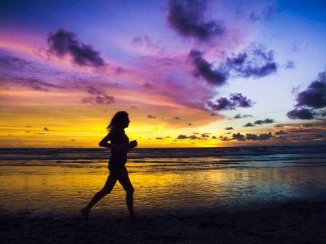 A silhouetted view of slim girl running for marathon on the beach under beautiful sunset