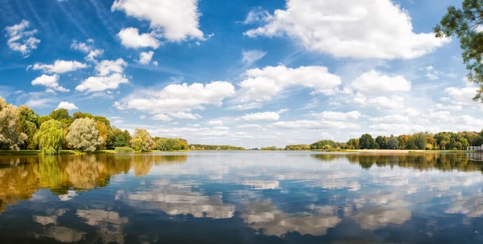 autumn park, trees and blue sky reflected in water, sunny day