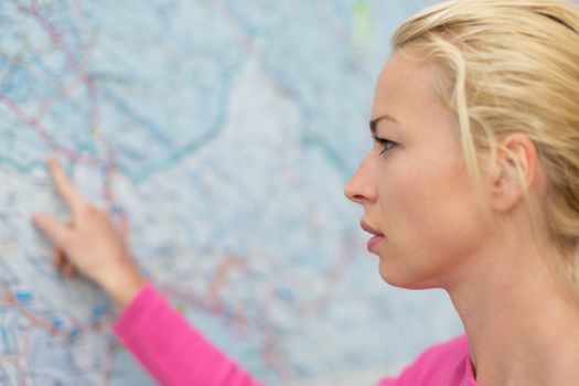 Woman orientating herself on the public transport map pointing on her final destination.