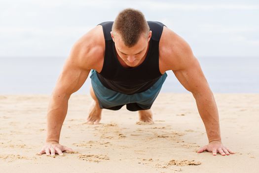 Sport, fitness. Man doing push-up on the beach