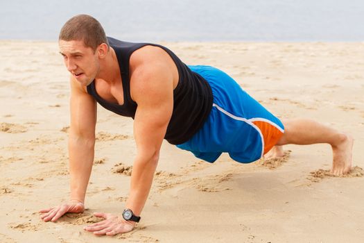 Sport, fitness. Man doing push-up on the beach