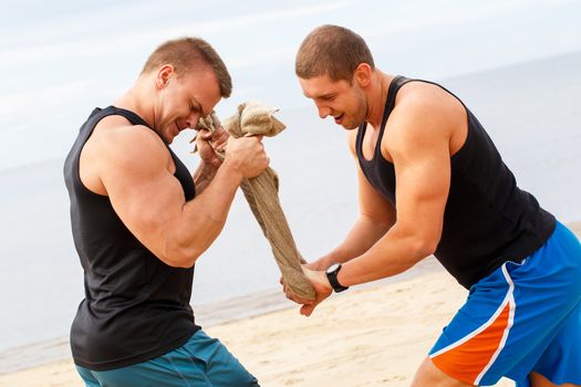 Sport, fitness. Bodybuilders during workout on the beach