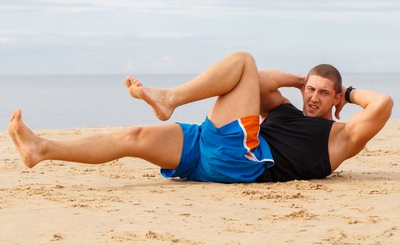 Sport, fitness. Bodybuilder during workout on the beach