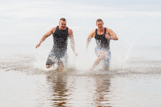 Two guys running on the beach