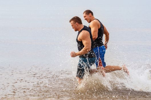 Two guys running on the beach