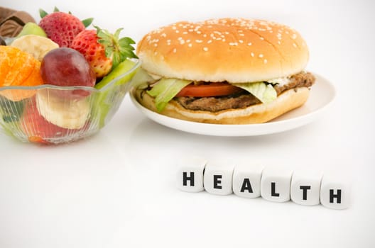 Health word on dices. Hamburger and fruits in babkground