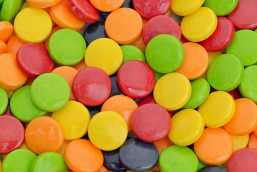 Close-up of green, yellow, red, orange and black round candies

