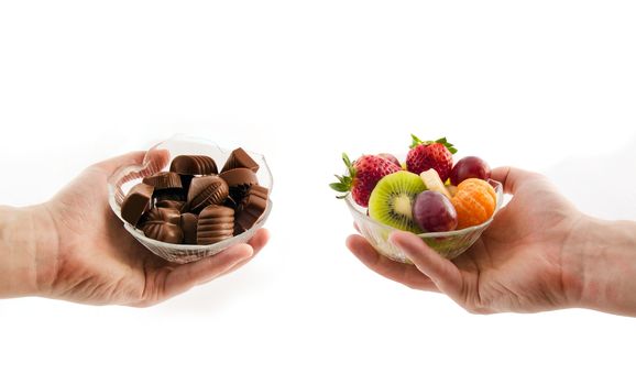 Choose healthy foods. Bowl with chocolates and a bowl of fruit