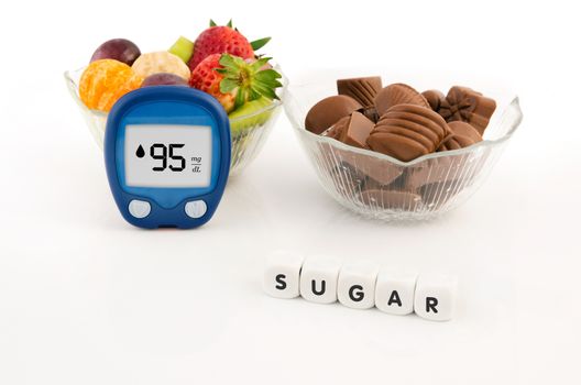 Glucometer and bowl with chocolates and fruits. Healthy lifestyle