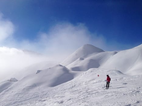 A skier on the piste in front of beautiful mountains