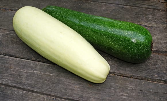 Green and white zucchini on a wooden table                               