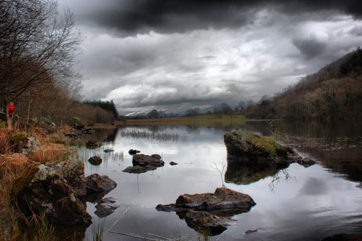 heavy clouds over a still lake in snowdonia