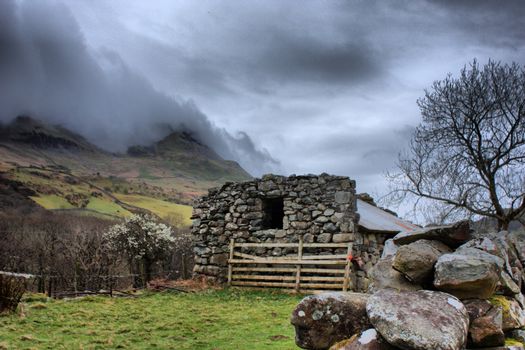 stone building in front of cadair idris mountain range in snowdonia