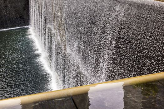 911 Memorial Pool Fountain Waterfall Reflections Abstract New York NY.  Pool is in the foundation of one of the Two World Trade Center Buildings.  Water falls into hole of the foundation.  