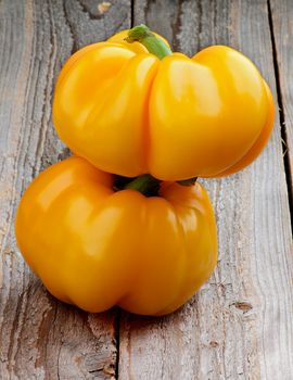 Stack of Two Big Unusual Shape Yellow Bell Peppers isolated on Rustic Wooden background