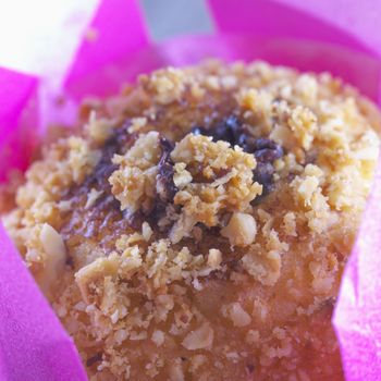 Chocolate muffin inside white and pink paper, strict close up