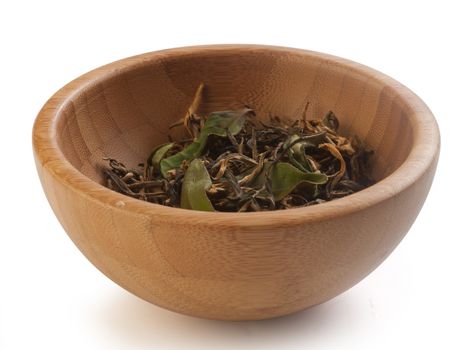 Brown dry and fresh green leaves of tea in the wooden bowl