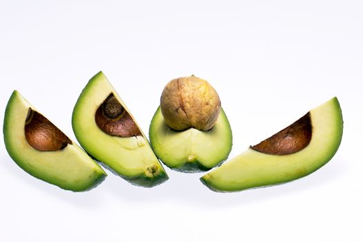 pieces of cut fresh avocado with stone isolated on white background