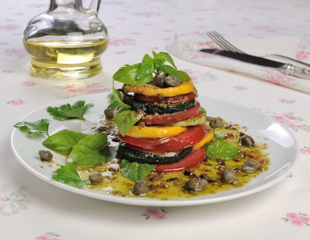 Appetizer of zucchini with tomato, pesto and capers