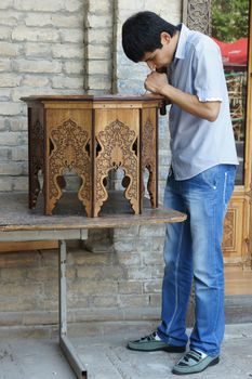 TASHKENT, UZBEKISTAN - MAY 18, 2012: Young furniture maker working on a traditional table on May 18, 2012 in Tashkent, Uzbekistan, Asia