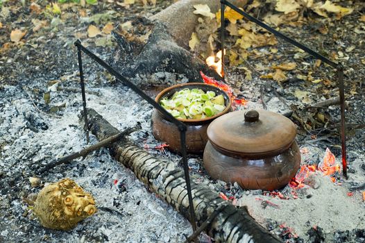 The roast in a clay pot over charcoal fire in nature