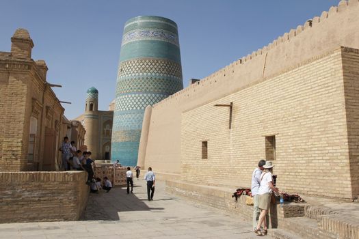 KHIVA, UZBEKISTAN - MAY 19, 2012: People in the historic district of Khiva with minaret Kalta Minor in the background on May 19, 2012 in Uzbekistan, Asia.                  