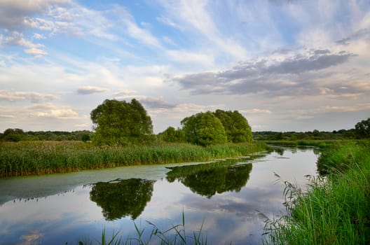 Summer landscape with river bend and clouds reflected in the water