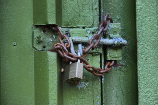 padlock and chain securing a green metal door