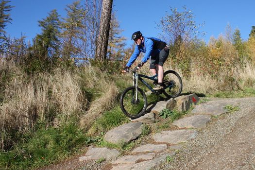 mountain biker in blue riding down a hill