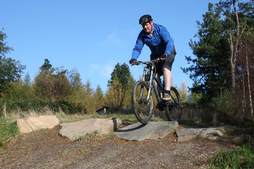 mountain biker in blue riding down a hill